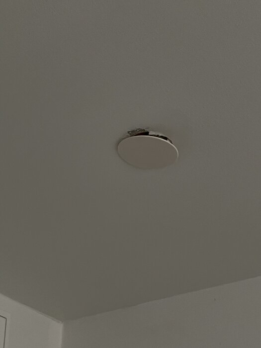 Övertäckt lamputtag i taket på lägenhet, med täcklock och synliga delar av ledningar.
