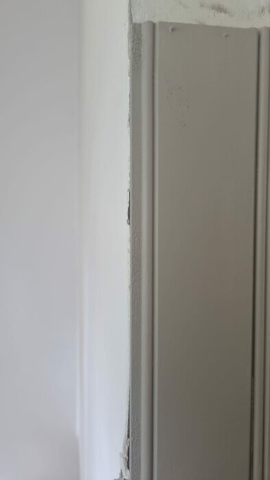 Närbild av ett hörn där en vägg med pärlspont möter en vanlig målad vägg. Hörnet är oavslutat och visar hur pärlsponten slutar.