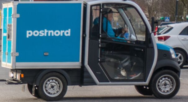 Postnord leveransbil parkerad med en förare bakom ratten.