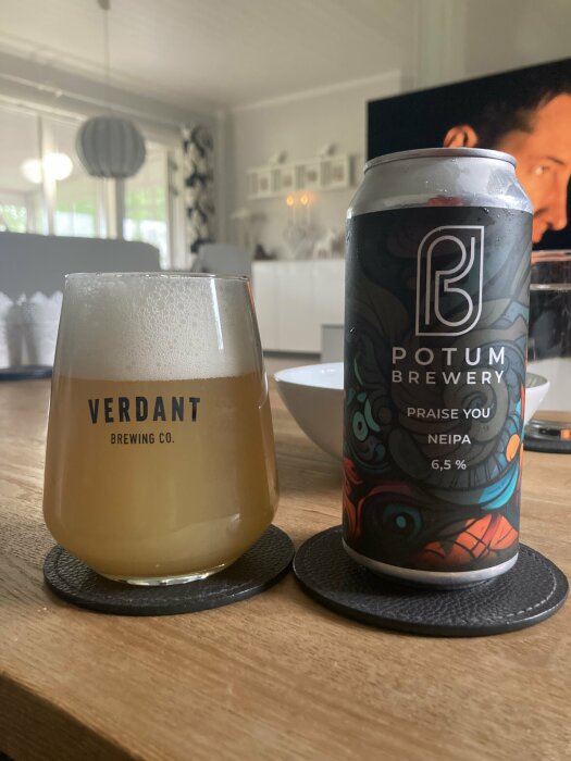 Ett glas öl från Verdant Brewing Co. och en burk Potum Brewery NEIPA står på ett träbord i ett vardagsrum.