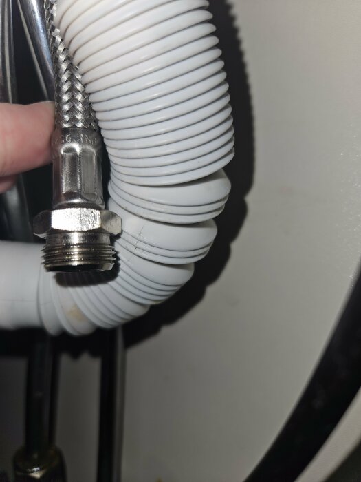 Flexible white drainage hose connected to a braided stainless steel water supply line with a male threaded fitting.