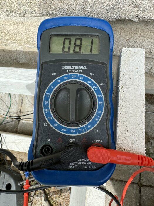 En digital multimeter visar ett värde på 0.81 Ohm medan den mäter resistansen i en begränsningskabel, med röd och svart mätkabel ansluten.