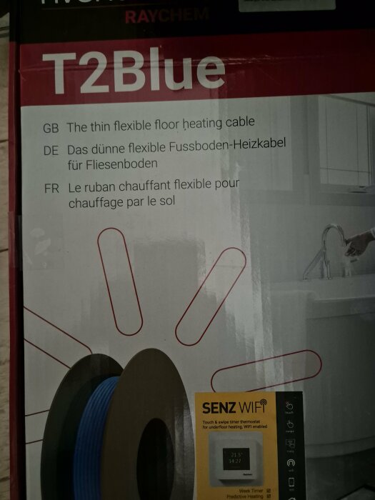 Förpackning för Raychem T2Blue, en tunn flexibel golvvärmekabel för kaklade golv, med instruktioner på engelska, tyska och franska samt bild av en termostat.