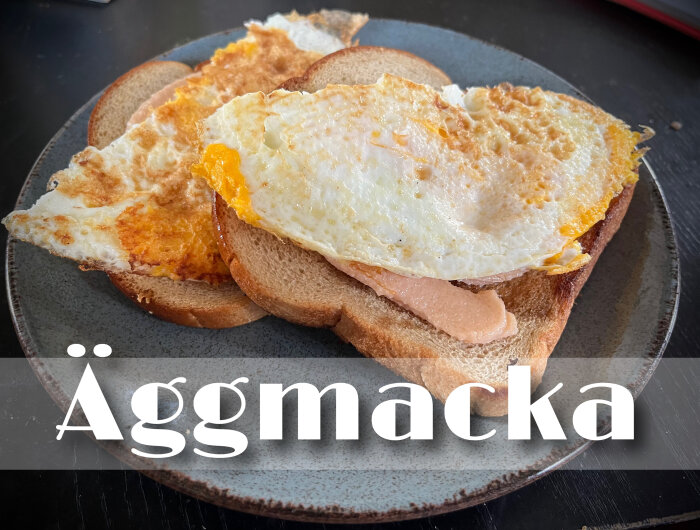 Två rostade brödskivor på en grå tallrik, toppade med stekta ägg och kaviar under texten "Äggmacka".