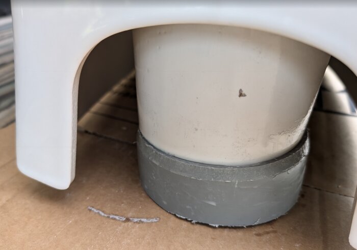 Närbild av en WC-anslutning från Ifö Spira, monterad på ett grått rör, som visar anslutningens tajta passform och de synliga måtten på cirka 103 mm.