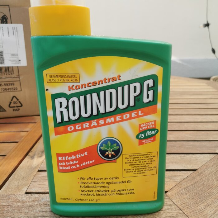 Flaska med koncentrerat bekämpningsmedel RoundUp G ogräsmedel på ett bord. Flaskans etikett anger att det är glyfosatbaserat och effektivt mot ogräs.