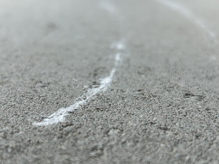 Närbild på ljusgrå betongplatta med vita skrapmärken.