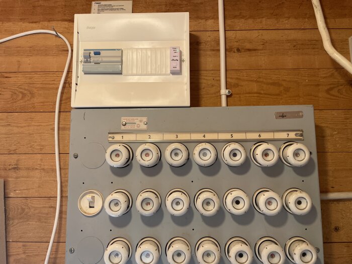 Nyinstallerad elcentral och gammal elcentral med porslinssäkringar monterad på vägg.