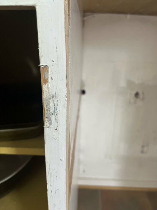 Ett närbildsfoto på en utdragen kökslåda i ett trångt utrymme som kräver breddning för att passa en diskmaskin.