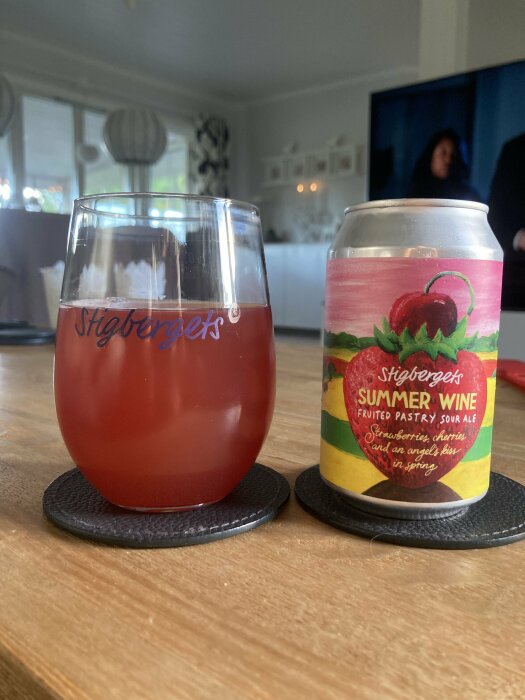 Ett glas och en burk av Stigbergets Summer Wine Fruited Pastry Sour Ale, placerade på ett bord i ett hem.