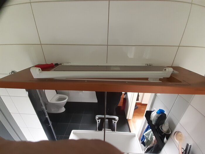 Spegelskåp i badrum med svagt lysande lysrör och verktyg synliga på hyllan. Fråga om ersättning eller reparation av lysrörsarmaturen.
