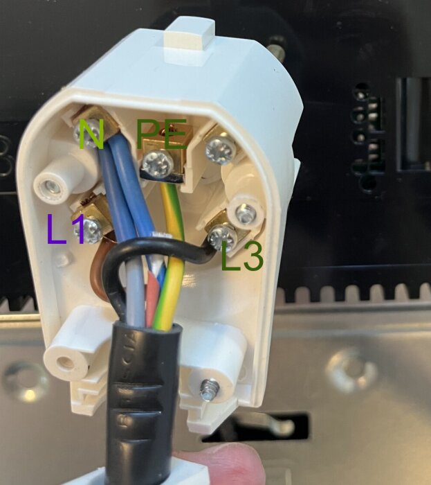 Närbild på elektrisk kontakt med skruvplintar märkta L1, L3, N och PE för elektriska anslutningar.