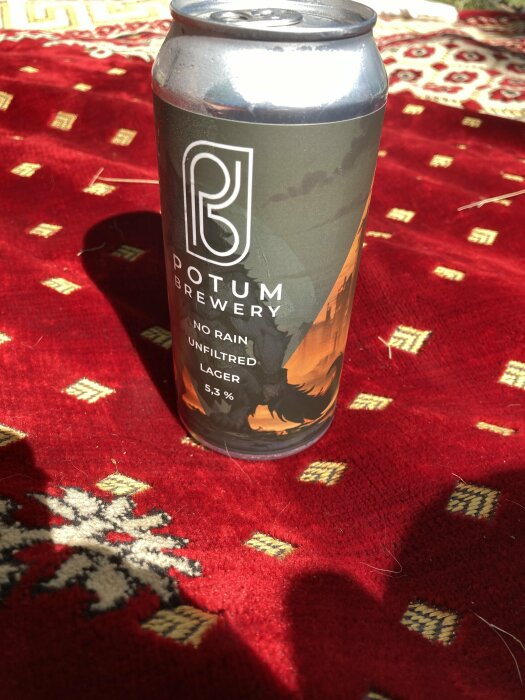 En burk Potum Brewery No Rain Unfiltered Lager på en röd mönstrad filt, med texten 5,3% på etiketten.