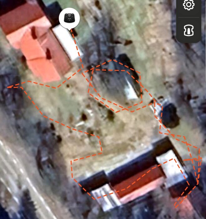 En satellitbild med staplade byggnader där en rutt för en gräsklippare visas med röda streckade linjer, som kör runt området och byter begränsningskabel.
