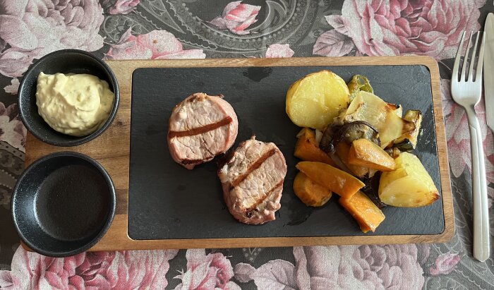 Grillad fläskfilé, ugnsstekta grönsaker (aubergine, sötpotatis, färskpotatis, squash, lök) och bearnaisesås serverat på en bricka.