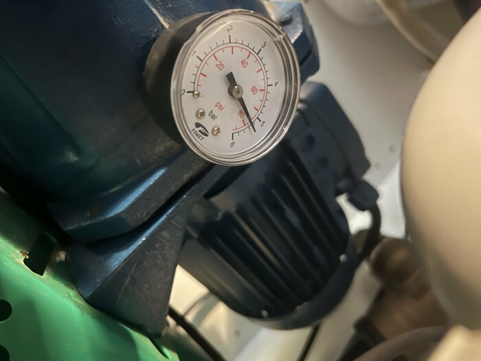 Närbild av en tryckmätare på en pump, med trycket visande cirka 52 psi.