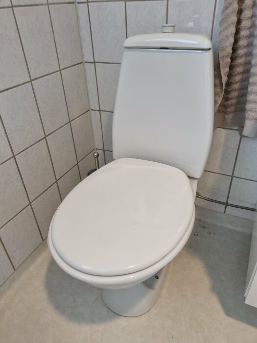 Vit toalettstol i ett kaklat badrum, där användaren vill justera spolmängden som nu är för låg, cirka 4 liter.