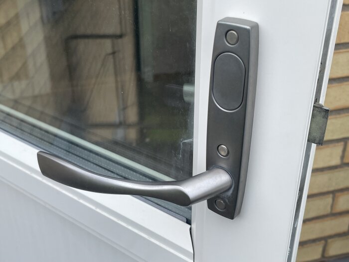 Handtag på en ytterdörr med sprucken yta och glapp, eventuellt av modellen Vinga 7314.