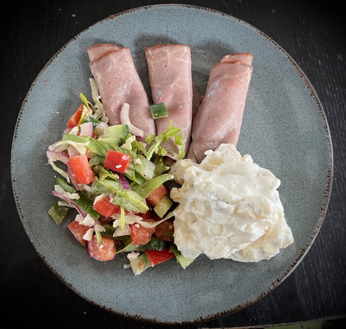 Tallrik med tre skivor rostbiff, sallad med grönsaker och en klick potatissallad. Klassisk sommarlunch beskriven i diskussionsinlägg.
