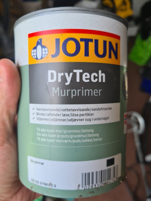 Hållande en burk av Jotun DryTech murprimer, som används för att förbereda ytor som ska målas.