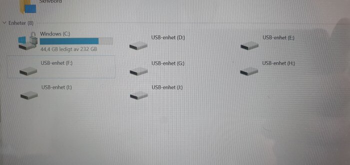 Skärmbild av en dator som visar åtta enheter under "Den här datorn", inklusive Windows (C:), USB-enhet (D:), och ytterligare USB-enheter från (E:) till (J:).