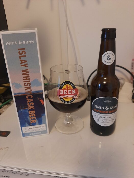 Flaska och låda Innis & Gunn Islay Whisky Cask Beer Limited Edition bredvid ett glas med samma öl, placerat på en bordsyta.