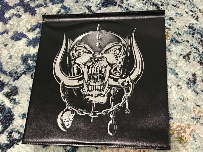 Motorhead-skivsamling med ett svart "läder"omslag och bandets ikonisk logotyp, en dödskalle med horn. Ligga på en mattbakgrund.