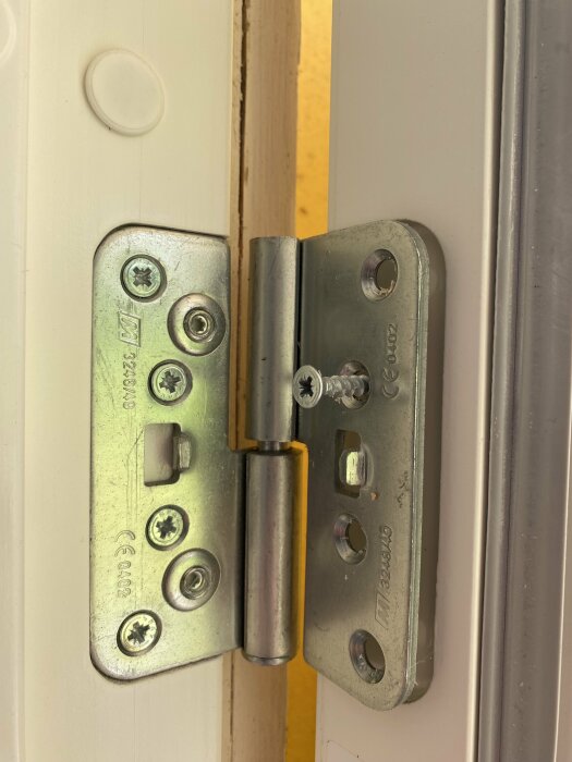 Gångjärn på en vit Diplomat-dörr, märkt med "M 3248/49", monterat på dörrkarmen. Insexskruvar och skruvhål är synliga.