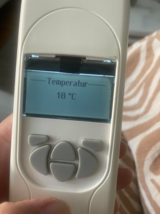 En termometer visar 18 grader Celsius på en elektronisk display.