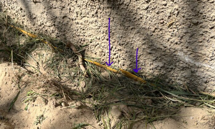 En täcklist ligger mot en putsad yta med gräs runtomkring. Två lila pilar pekar mot där listen möter putsen, vilket tyder på dålig tätning.