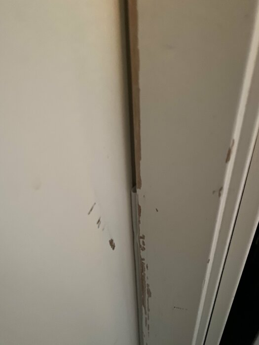 Nära bild av dörrkarm med tätningslist som inte sitter tätt. Viss skada på dörrkarmens färg och dörren visar tecken på att ha blivit för tight när dörren stängts.