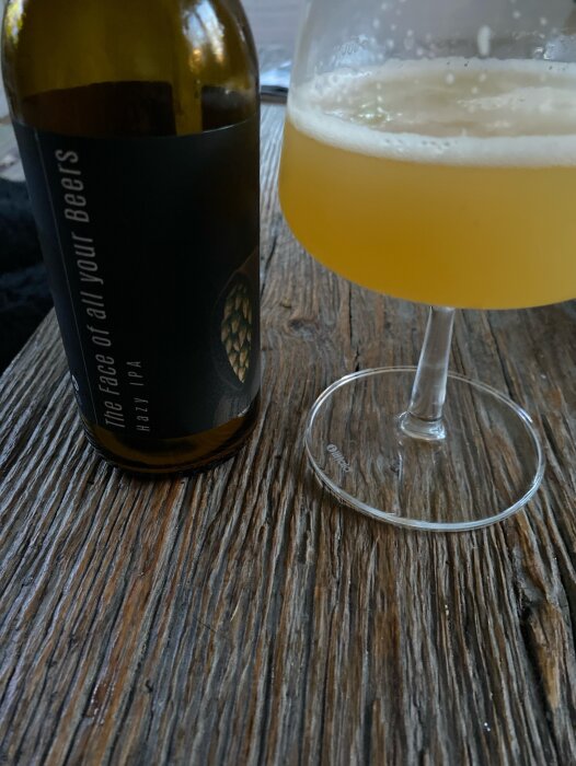 En flaska öl från Krypta micro bryggeri och ett glas med skummande öl på ett rustikt träbord.