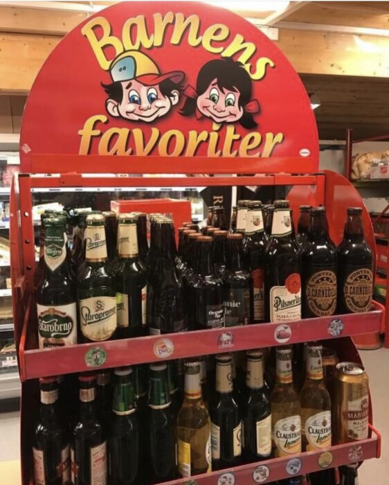 En hylla med ölflaskor under en skylt där det står "Barnens favoriter" med tecknade figurer.