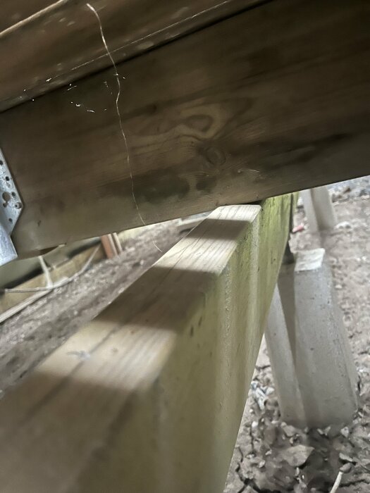 En sned regel under en träaltan med betongstöd synlig i bakgrunden.