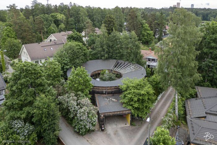 Luftfotografi av en unik, rund byggnad omgiven av träd och andra hus i ett grönområde i Helsingfors.