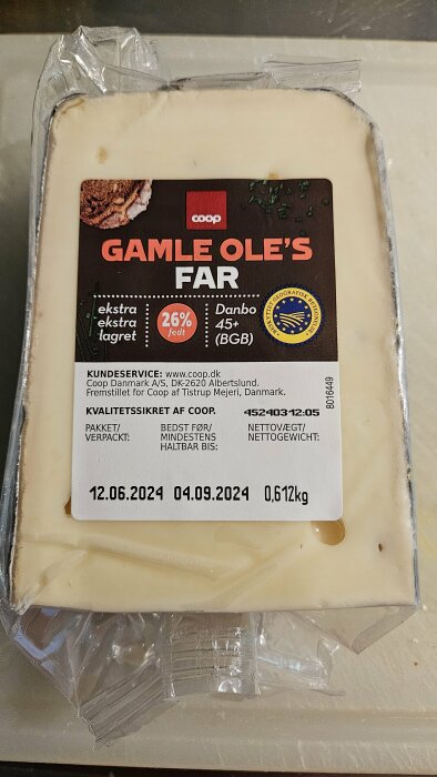 Förpackning av den danska osten "Gamle Ole's Far", ekstra ekstra lagret, från Coop. Den väger 0,612 kg och har bäst-före datum 12.06.2024 och 04.09.2024.