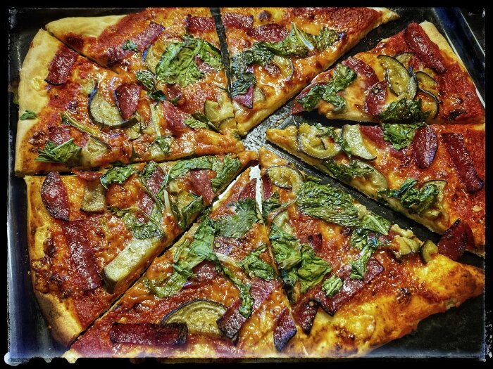 Hemlagad pizza med mangold och aubergine, skuren i skivor på bakplåt.