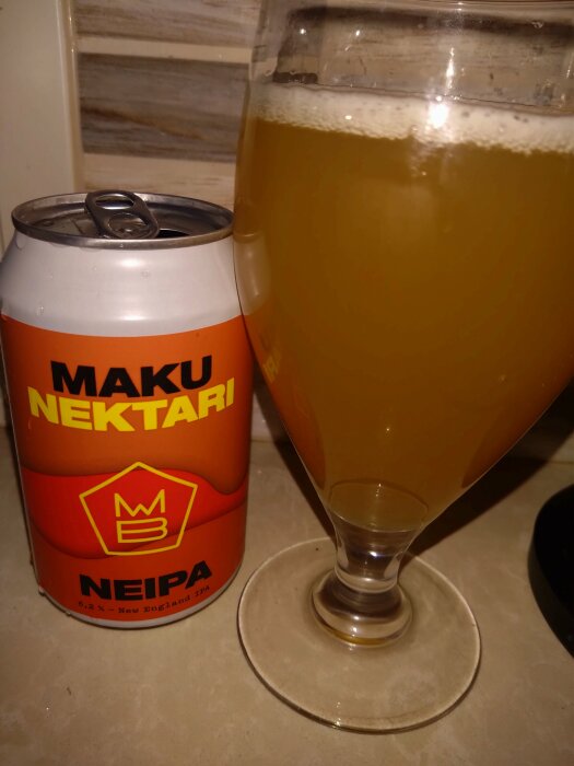 En burk öl märkt "Maku Nektari NEIPA" bredvid ett fullt glas av samma öl. Märket har en orange etikett med gul text.