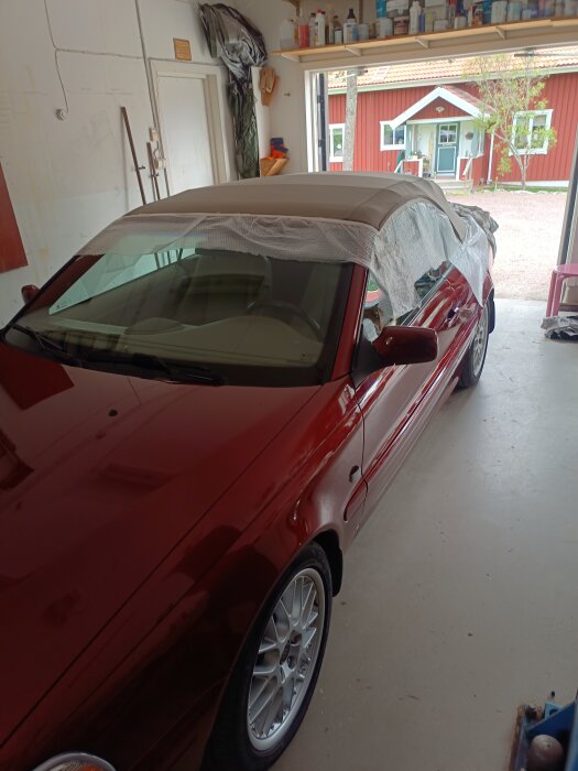 Röd Volvo C70 cabriolet i ett garage, med täckt cab använt för impregnering. Bilen är nytvättad och har BBS Propus split fälgar.