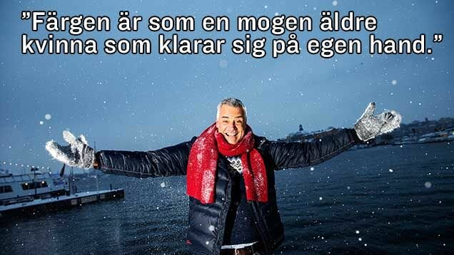 En man i vinterkläder står med utsträckta armar framför ett snötäckt vattenlandskap, med ett citat om färg ovanför honom.