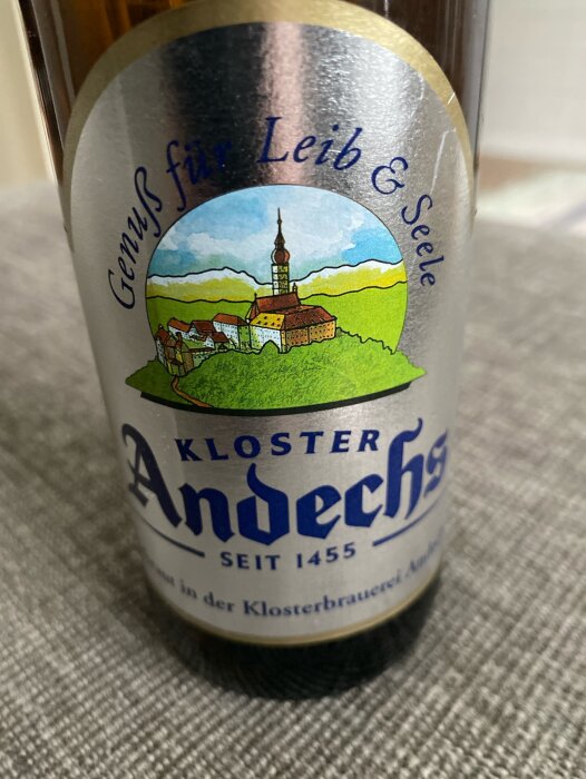 Flaska med etikett från Kloster Andechs öl, med en illustration av ett kloster och texten "Genuss für Leib & Seele" samt "SEIT 1455".