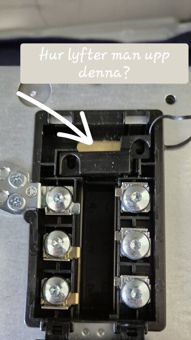 Kabelavlastare i närbild med texten "Hur lyfter man upp denna?" och en pil som pekar på en del av kabelavlastaren.