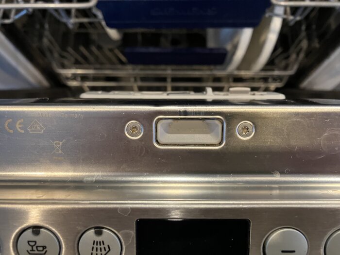 Närbild på låsstift och låsdetaljer på dörren av en Siemens diskmaskin, med öppen lucka och diskkorgar synliga i bakgrunden.
