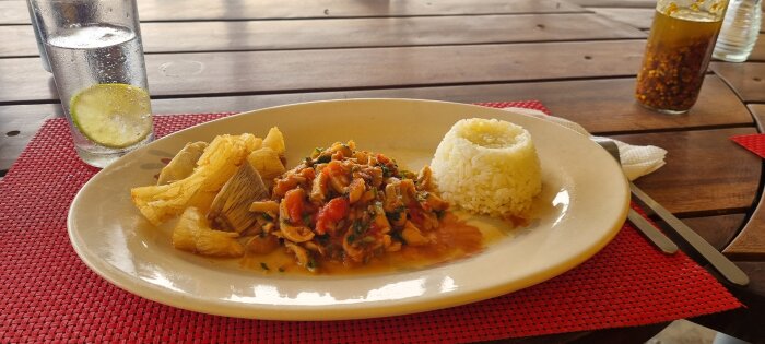 Tallrik med Marisca (stor musla) tillagad med grönsaker och kryddor, serverad med friterad mandioka (Casava) och ris.