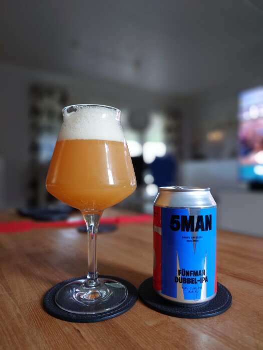 Ett glas med skummande öl bredvid en burk 5Man Fünfman Dubbel-IPA på ett träbord, med texten "5Mans bryggeri Borlänge".