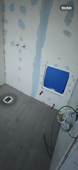 Omonterat fördelarskåp/vattenskåp under byggnation med synliga rör och kablar på en vägg med pågående spackelarbete.