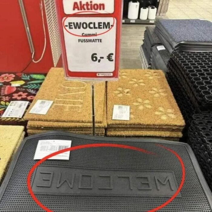 Dörrmatta i en butik, märkt "Aktion Fussmatte 6,-€". Mattan har feltrycket "EWOCLEM" istället för "WELCOME".