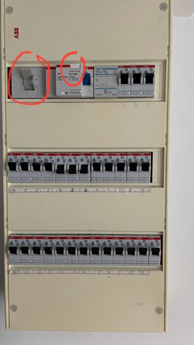 Bilden visar ett elskåp med flera kretsbrytare, där två av brytarna är inritade med röd cirkel och står i läge "on".