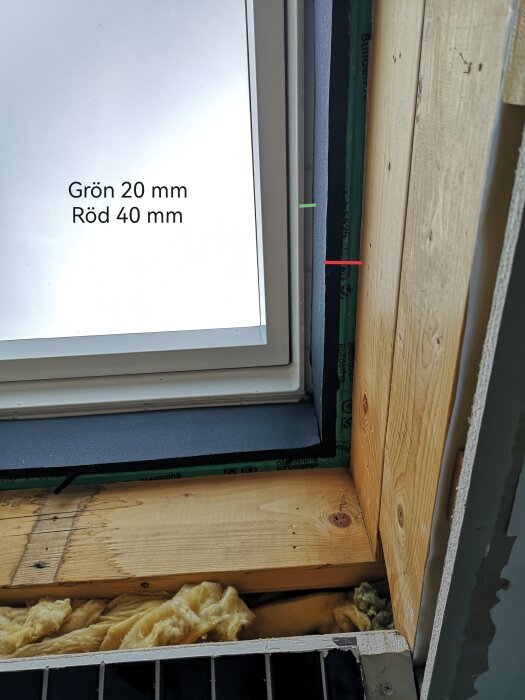 Nyinstallerat takfönster med underbeslag i ett badeväring, visar olika lager av isolering runt fönstret och mått i millimeter, 20 mm gul och 40 mm röd markering.