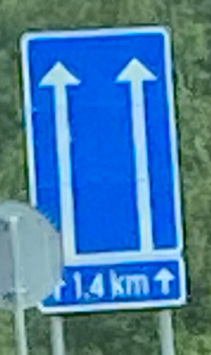 Vägskylt på E12 i Finland som visar två pilar rakt upp och texten "1.4 km".